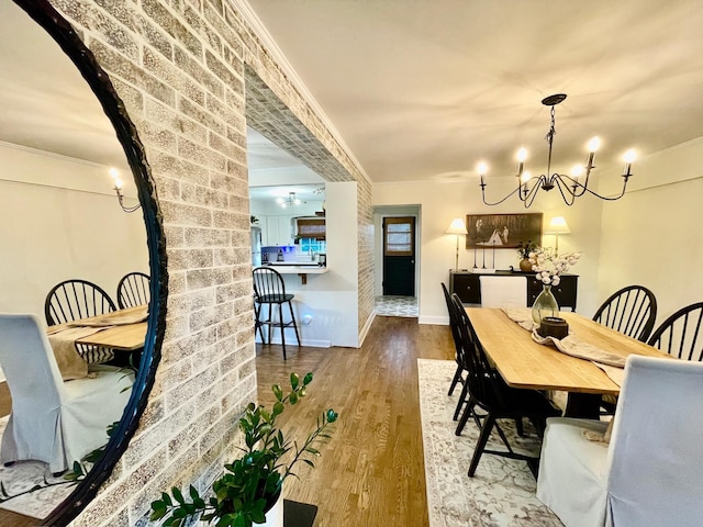 dining room featuring an inviting chandelier, crown molding, wood finished floors, and baseboards