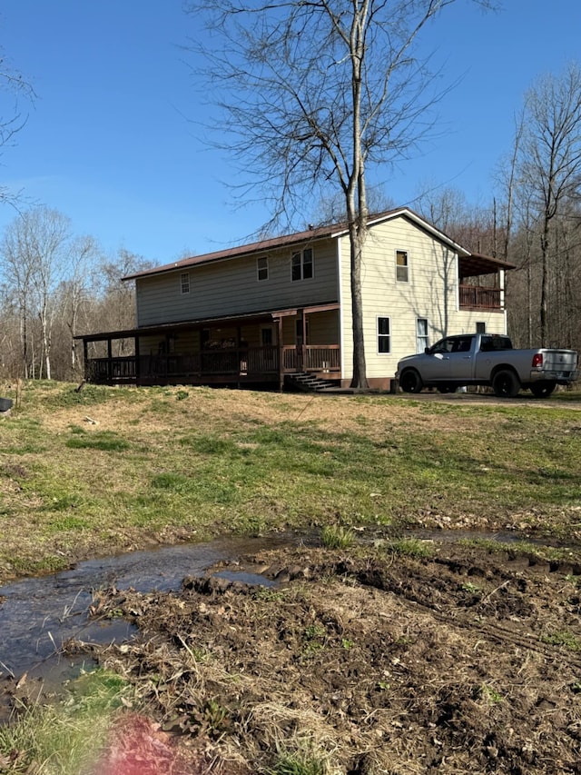 rear view of house with covered porch and a lawn