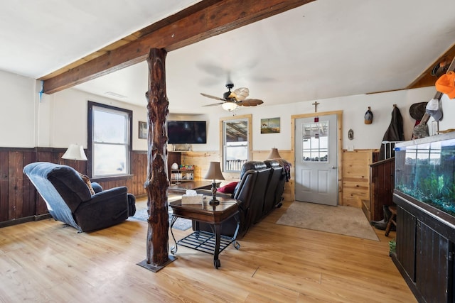 living room with visible vents, a wainscoted wall, light wood-type flooring, beam ceiling, and a ceiling fan