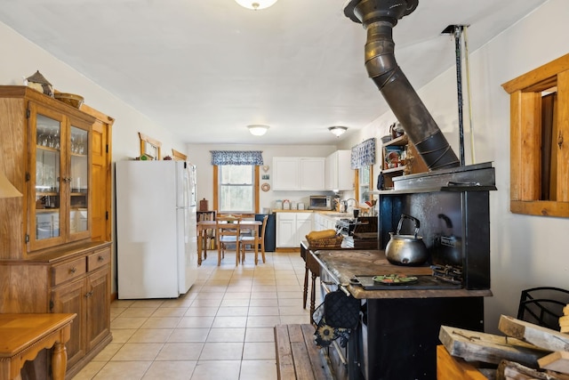 kitchen featuring freestanding refrigerator, light tile patterned flooring, white cabinets, light countertops, and glass insert cabinets