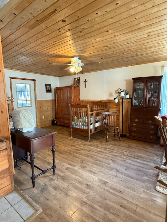 bedroom with wood finished floors, wooden walls, wood ceiling, and wainscoting