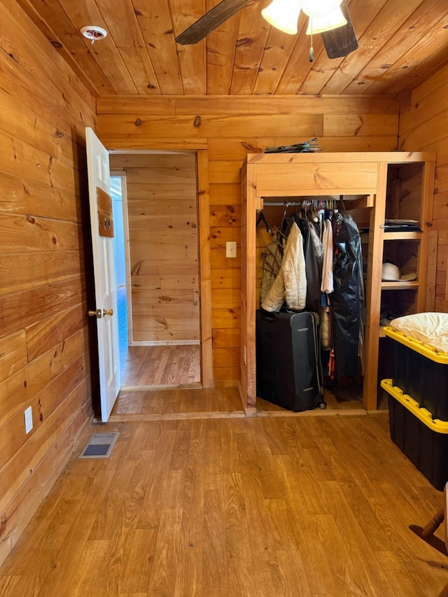 unfurnished bedroom featuring visible vents, wooden ceiling, wooden walls, and wood finished floors