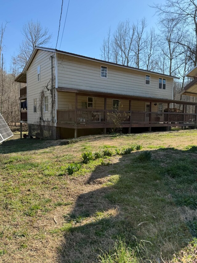 back of property with a lawn and a deck