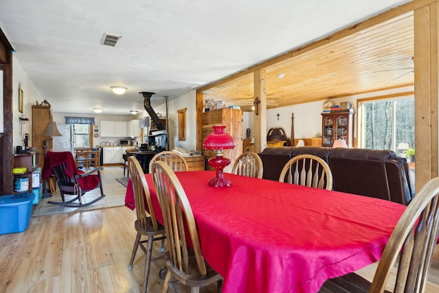 dining area featuring visible vents, a ceiling fan, a wood stove, and light wood-style floors