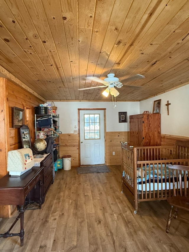 bedroom featuring wood ceiling, wood finished floors, and wainscoting