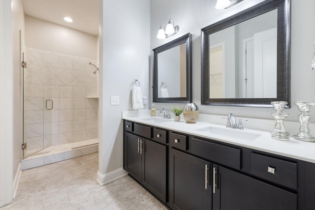 bathroom with a shower stall, double vanity, baseboards, and a sink