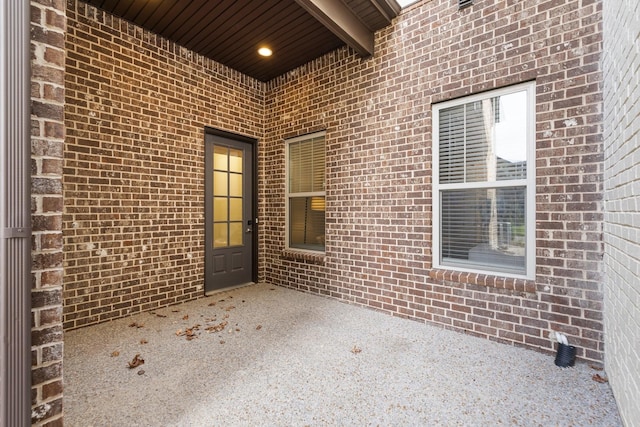 property entrance featuring brick siding and a patio