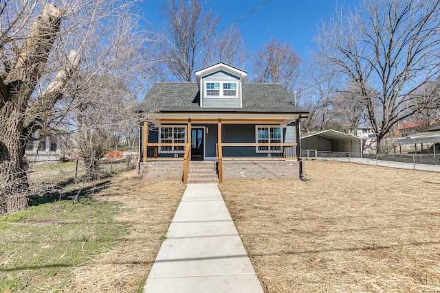 bungalow featuring a porch, a detached carport, and fence