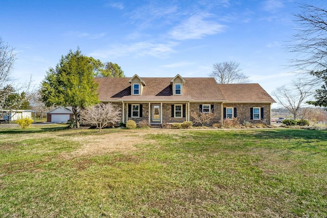 new england style home with a front lawn, brick siding, and roof with shingles