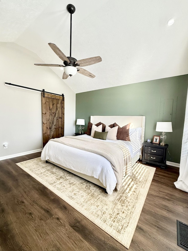 bedroom featuring visible vents, baseboards, a barn door, vaulted ceiling, and dark wood-style floors