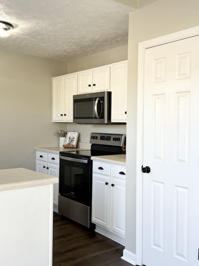 kitchen with appliances with stainless steel finishes, white cabinetry, light countertops, and dark wood-style flooring