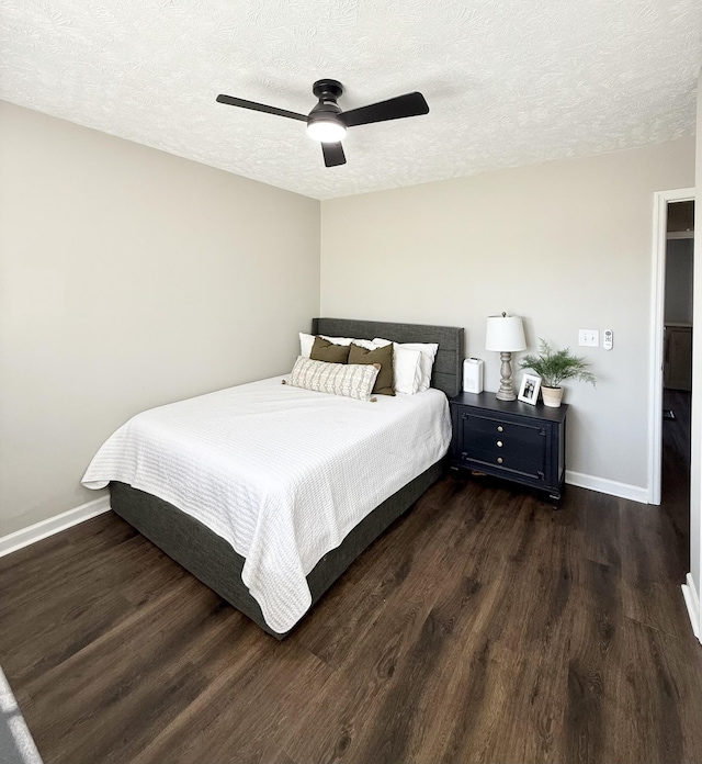 bedroom featuring ceiling fan, a textured ceiling, baseboards, and wood finished floors