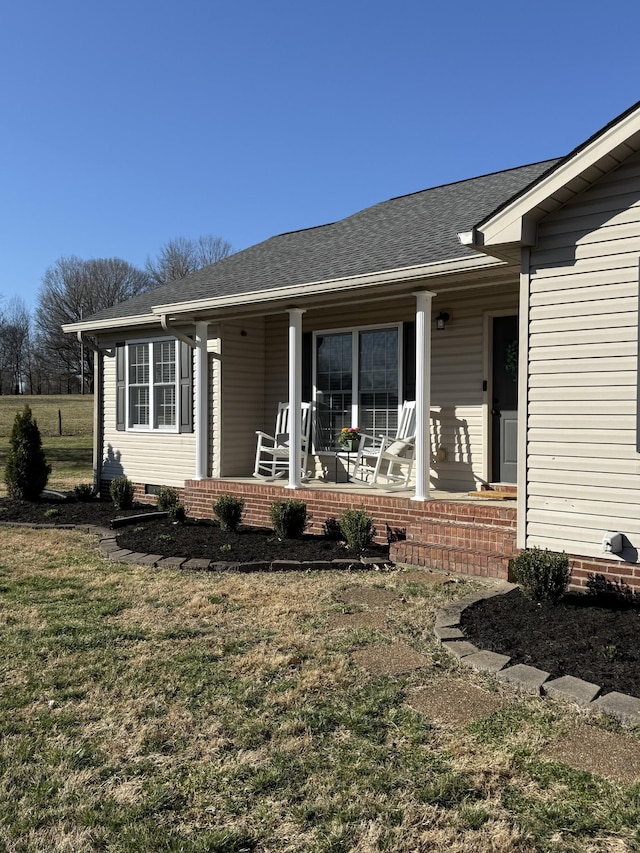 exterior space with a shingled roof, a porch, a yard, and crawl space