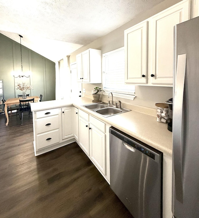 kitchen with a sink, a textured ceiling, dark wood-style floors, and stainless steel appliances