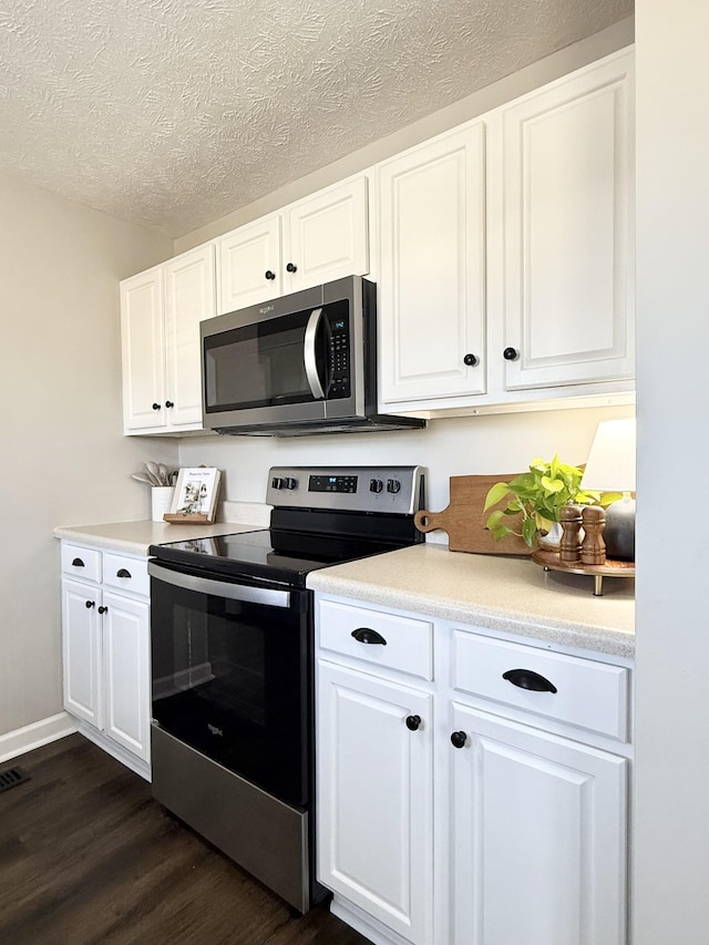 kitchen featuring white cabinets, appliances with stainless steel finishes, light countertops, and dark wood-type flooring