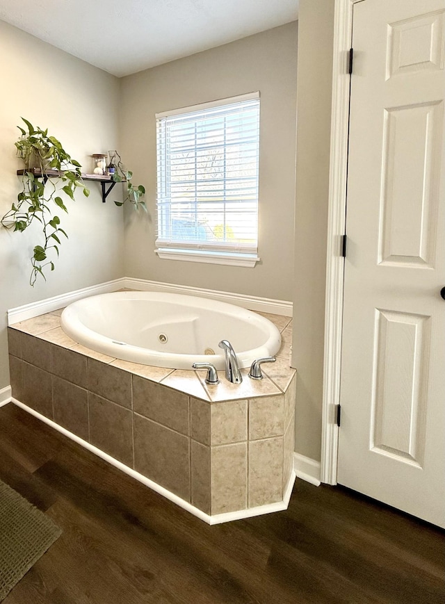 full bathroom with baseboards, a jetted tub, and wood finished floors