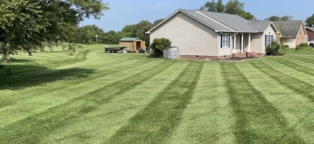 view of side of property with a storage shed, a yard, an outbuilding, and crawl space