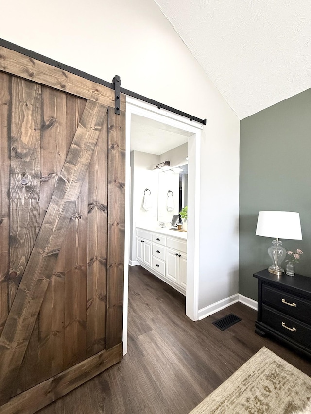 bathroom featuring vanity, wood finished floors, visible vents, baseboards, and vaulted ceiling