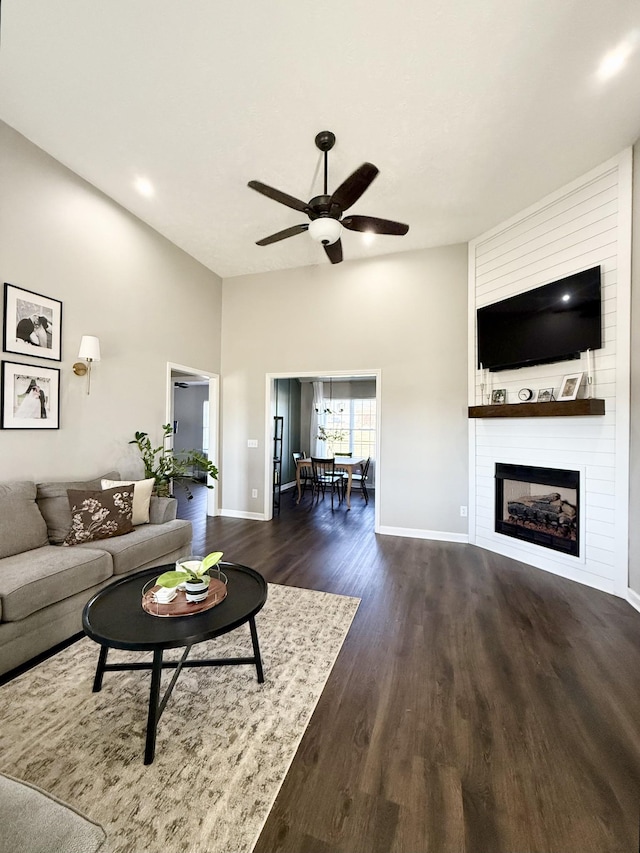 unfurnished living room featuring baseboards, a ceiling fan, dark wood-style floors, and a fireplace