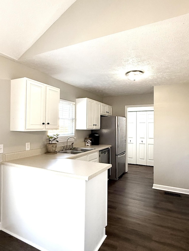 kitchen with a sink, a peninsula, white cabinets, and light countertops