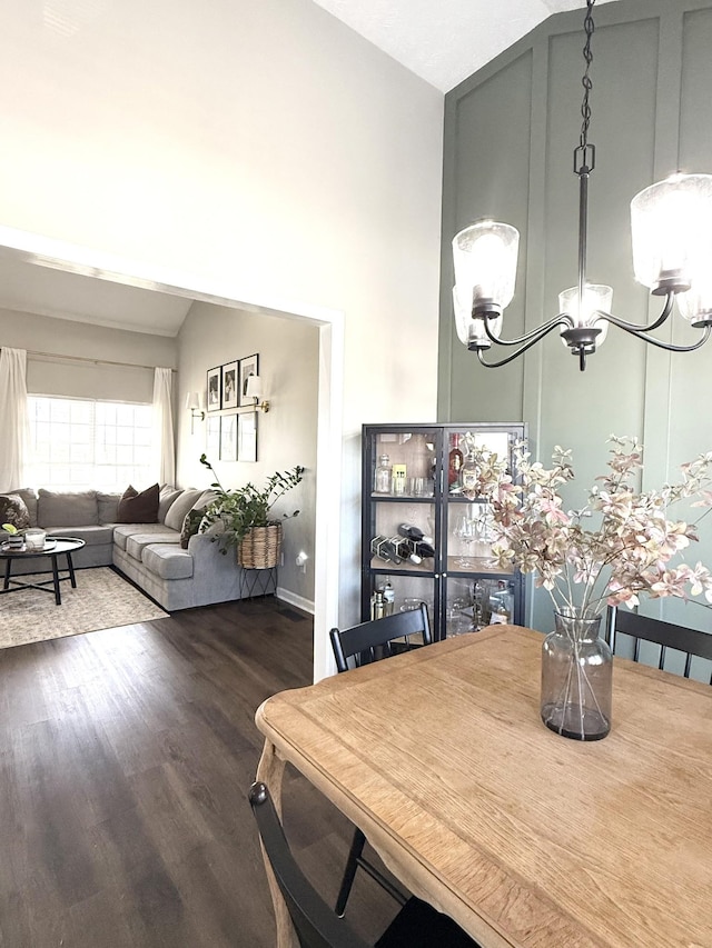 dining space with dark wood finished floors, a notable chandelier, and high vaulted ceiling