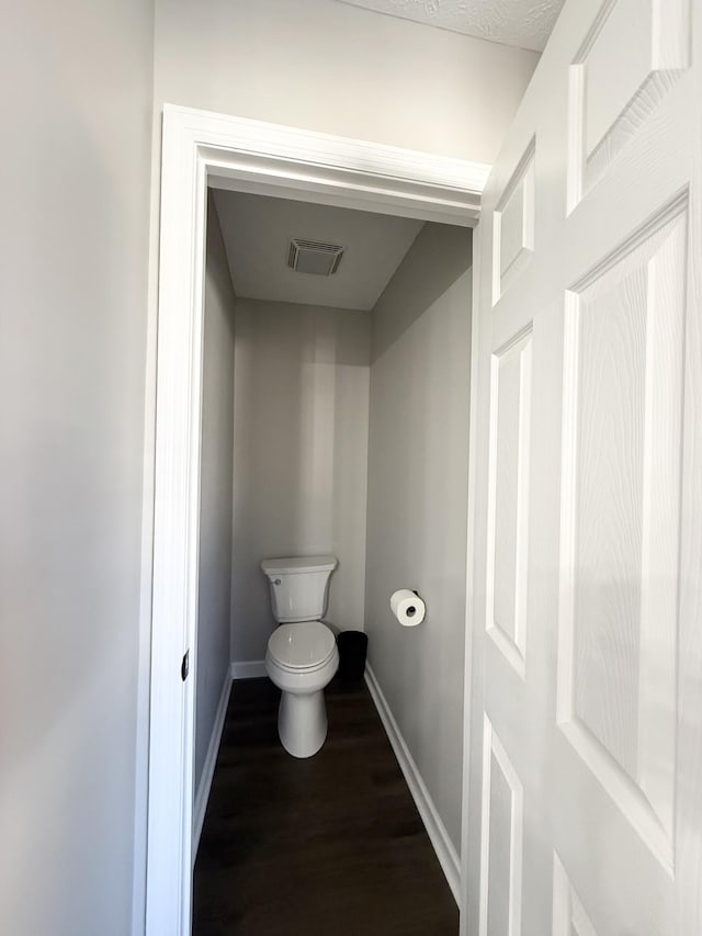 bathroom featuring visible vents, toilet, wood finished floors, and baseboards