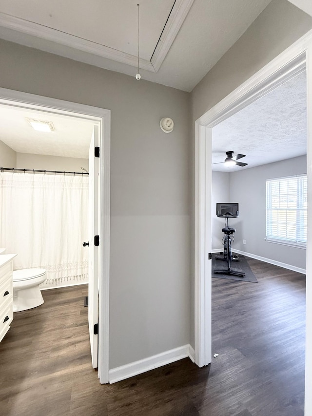 corridor with dark wood-style floors, attic access, and baseboards