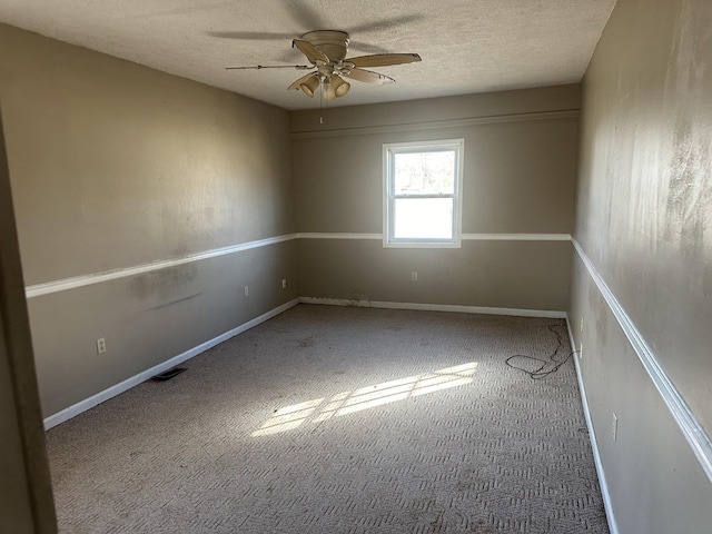 carpeted empty room with ceiling fan, baseboards, and a textured ceiling