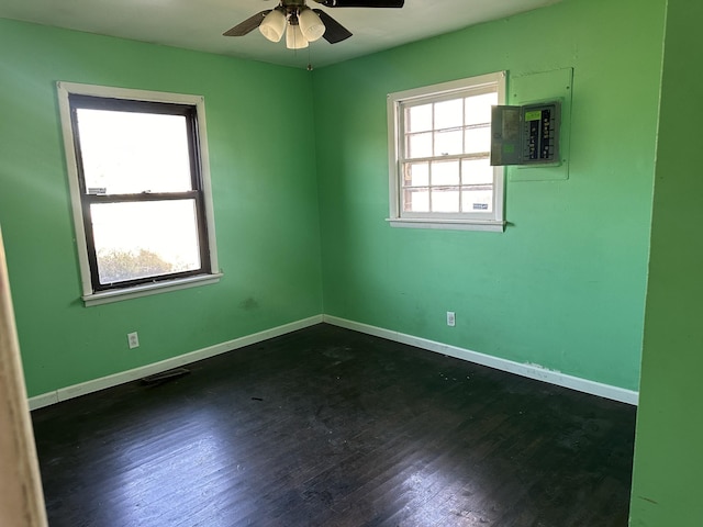 spare room with electric panel, a ceiling fan, baseboards, and dark wood-style flooring