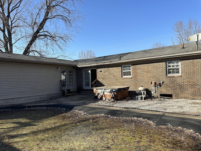 back of house featuring brick siding and entry steps