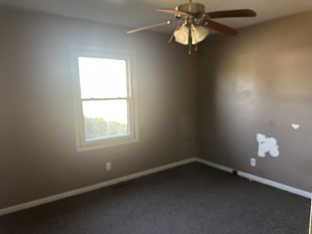 spare room with dark carpet, a ceiling fan, and baseboards