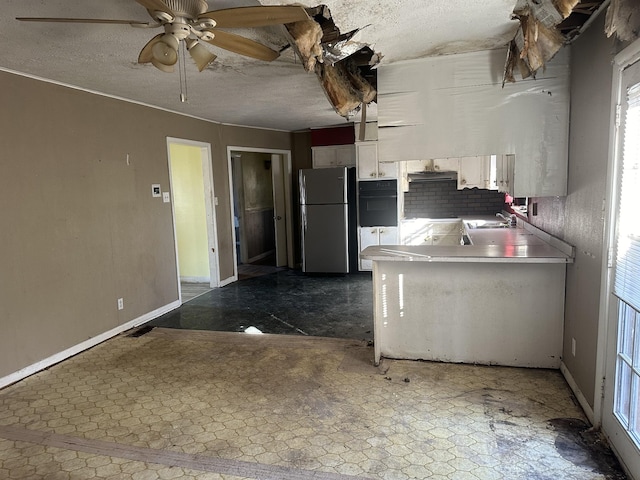 kitchen featuring a textured ceiling, dark floors, freestanding refrigerator, and a sink