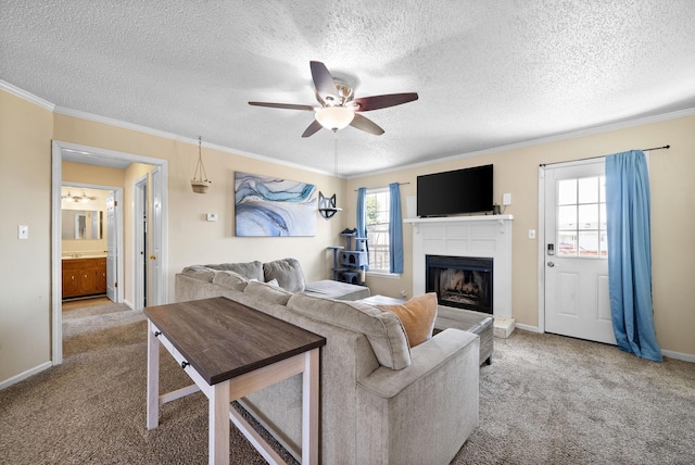 carpeted living room featuring baseboards, a fireplace with raised hearth, ceiling fan, ornamental molding, and a textured ceiling