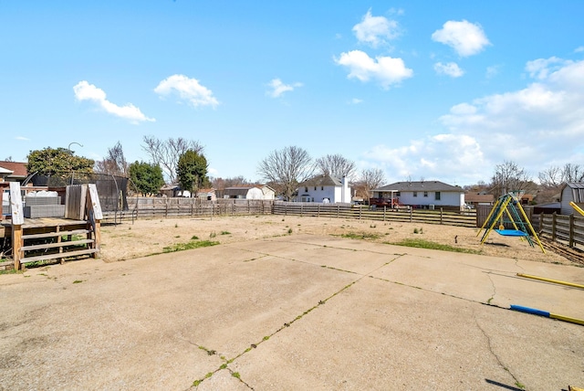 view of yard featuring a deck, a playground, and fence