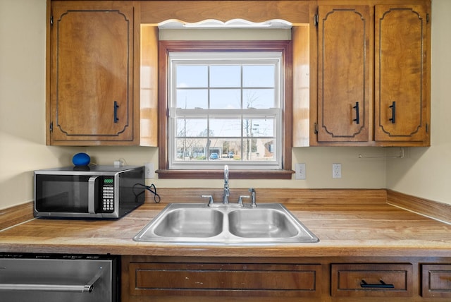 kitchen with a sink, stainless steel appliances, brown cabinets, and light countertops