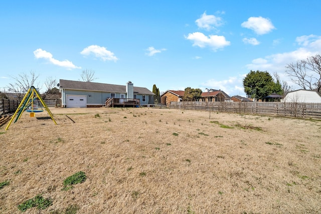 view of yard featuring a playground, a deck, and fence