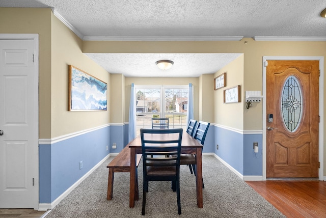 dining room featuring baseboards, a textured ceiling, wood finished floors, and ornamental molding