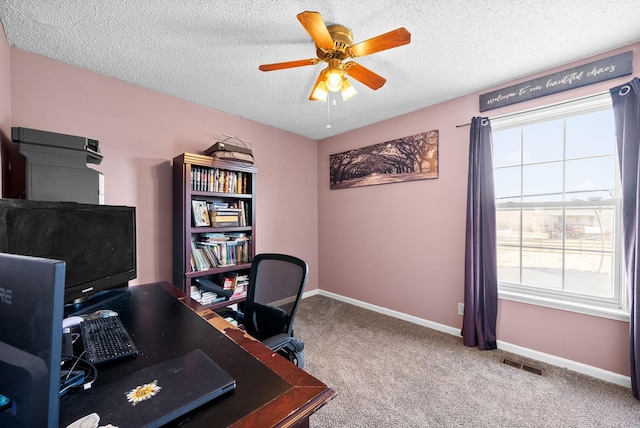 office area featuring visible vents, a textured ceiling, carpet flooring, baseboards, and ceiling fan