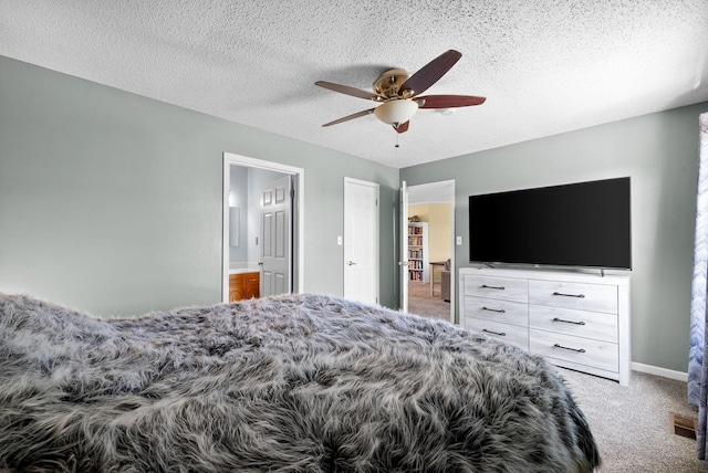 bedroom featuring visible vents, ceiling fan, carpet, ensuite bath, and a textured ceiling