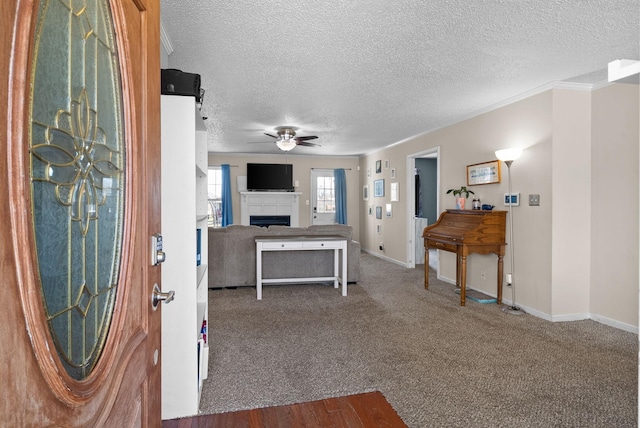 entrance foyer with baseboards, dark carpet, ceiling fan, and a fireplace