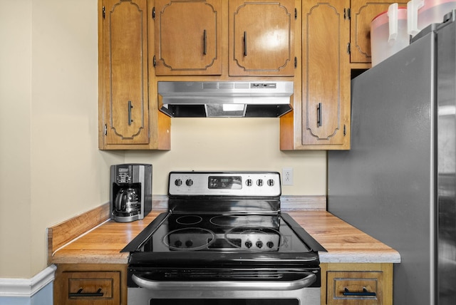 kitchen with under cabinet range hood, brown cabinets, and appliances with stainless steel finishes