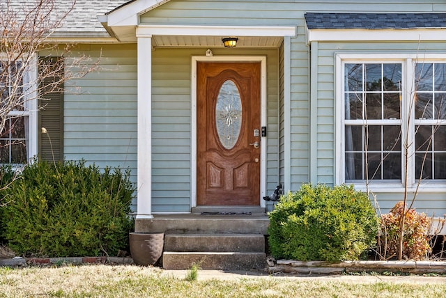 view of exterior entry featuring roof with shingles