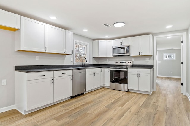 kitchen with dark countertops, white cabinets, visible vents, and stainless steel appliances