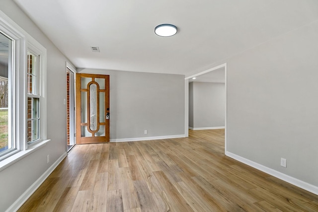 unfurnished room featuring light wood-type flooring, visible vents, and baseboards