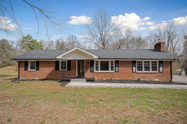 single story home featuring brick siding, a chimney, and a front yard