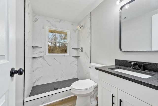 full bath featuring vanity, toilet, wood finished floors, and a marble finish shower