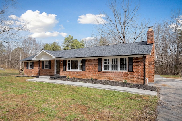 single story home with brick siding, a chimney, a front lawn, and roof with shingles