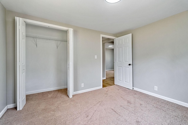 unfurnished bedroom featuring baseboards, carpet floors, and a closet