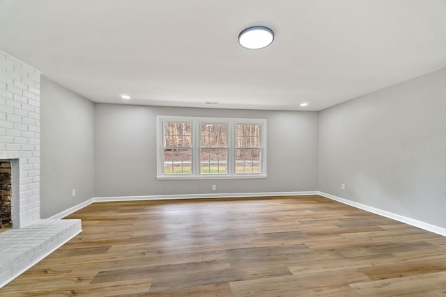 unfurnished living room with recessed lighting, baseboards, light wood-style floors, and a fireplace