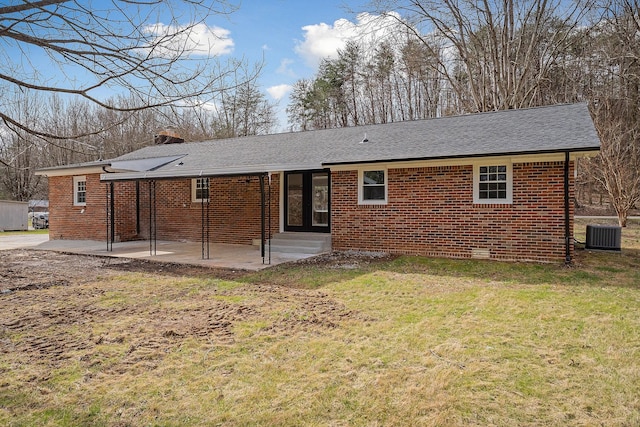 rear view of property featuring a patio, a chimney, entry steps, a lawn, and brick siding